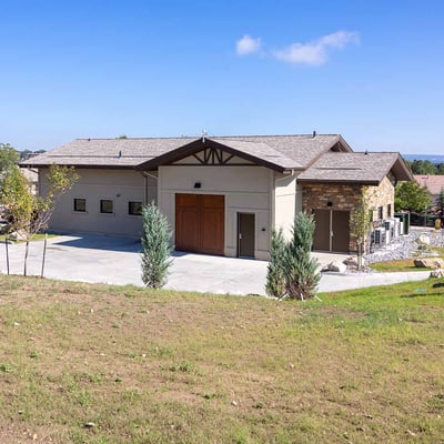 A stucco building resembling a suburban, single-family home with a driveway and landscaping surrounding it.