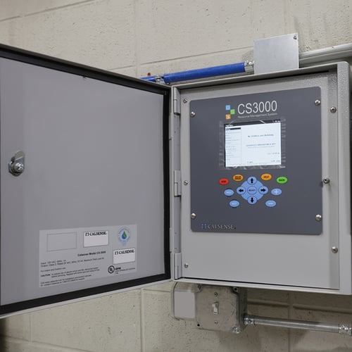 Open grey control panel box of a large irrigation controller. There is a screen and a directional pad of buttons below the model number which is "CS3000."