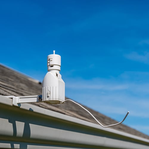 A photo of a rain sensor, a cylindrical piece of outdoor equipment attached to a roof gutter