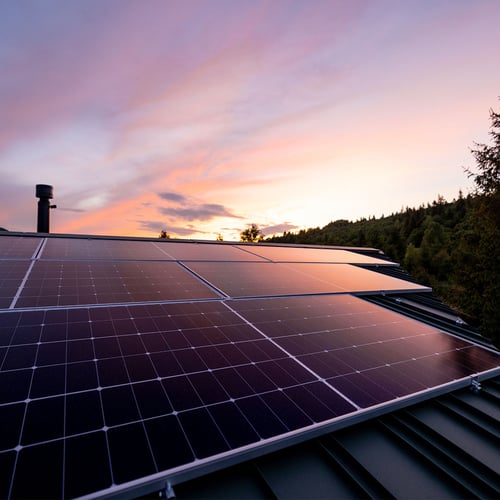 Rooftop solar panels photographed at sunset.