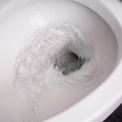 Close up shot of clean water flushing down the drain of a toilet.