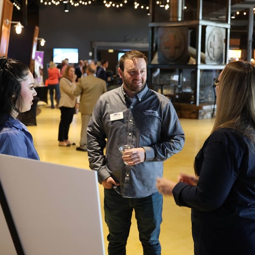 A Colorado Springs Utilities employee stands and talks to two customers at a community event.
