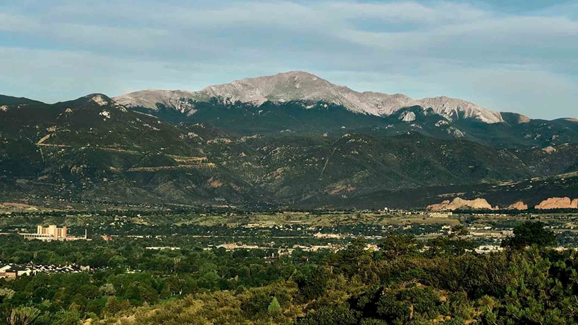 Scenic view of Pikes Peak as taken from a Palmer Park in Colorado Springs under sunny skies. Garden of the Gods is visible from a distance in the lower right corner of the photo.