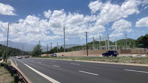 Rendering of the proposed Central Substation looking west from Austin Bluffs Parkway. A tall fence surrounds electric equipment below power lines.