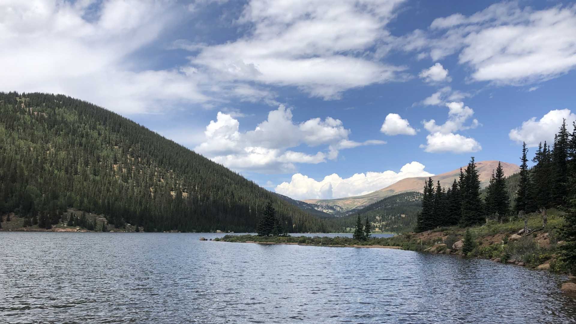 A mountainside lake flanked by pines on both sides.