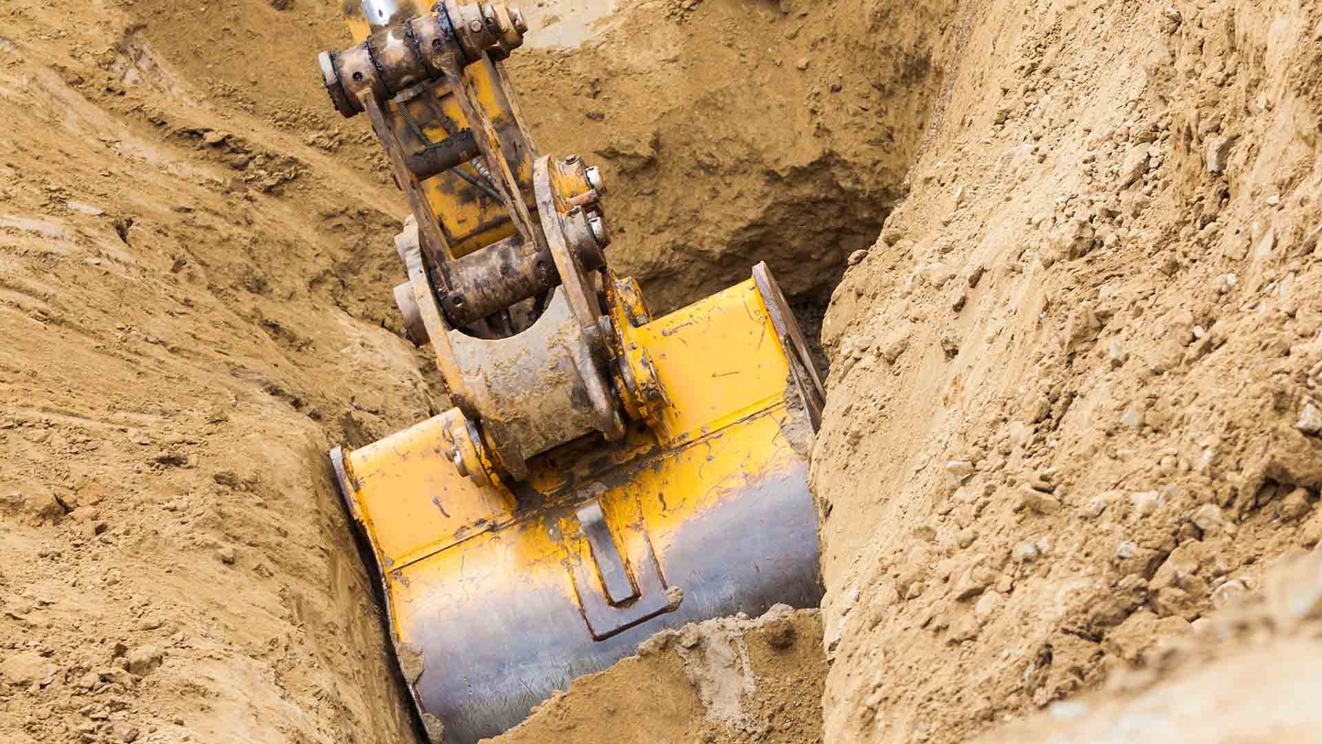Photo of an excavator bucket digging into the ground.
