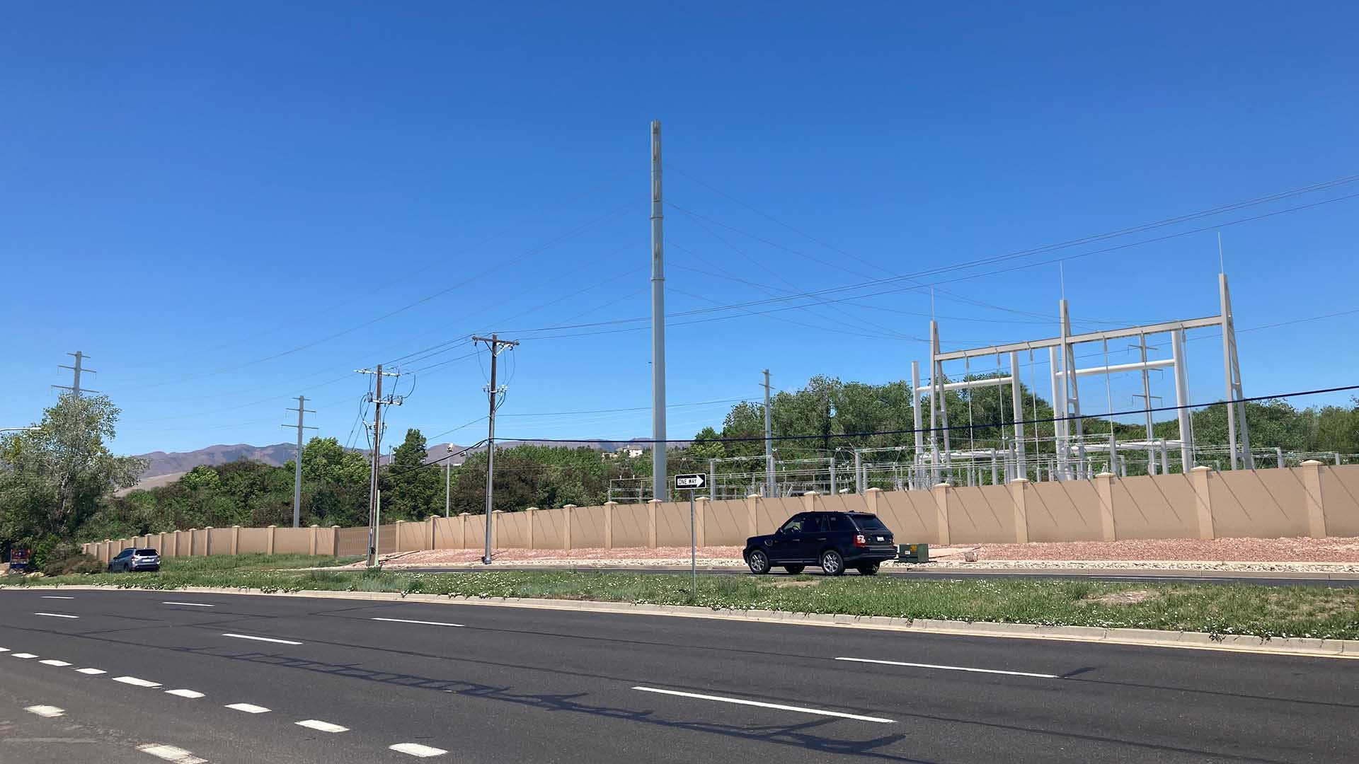Rendering of the Central Bluffs Substation looking southwest from Austin Bluffs Parkway. A tall beige fence surrounds electric equipment below power lines.