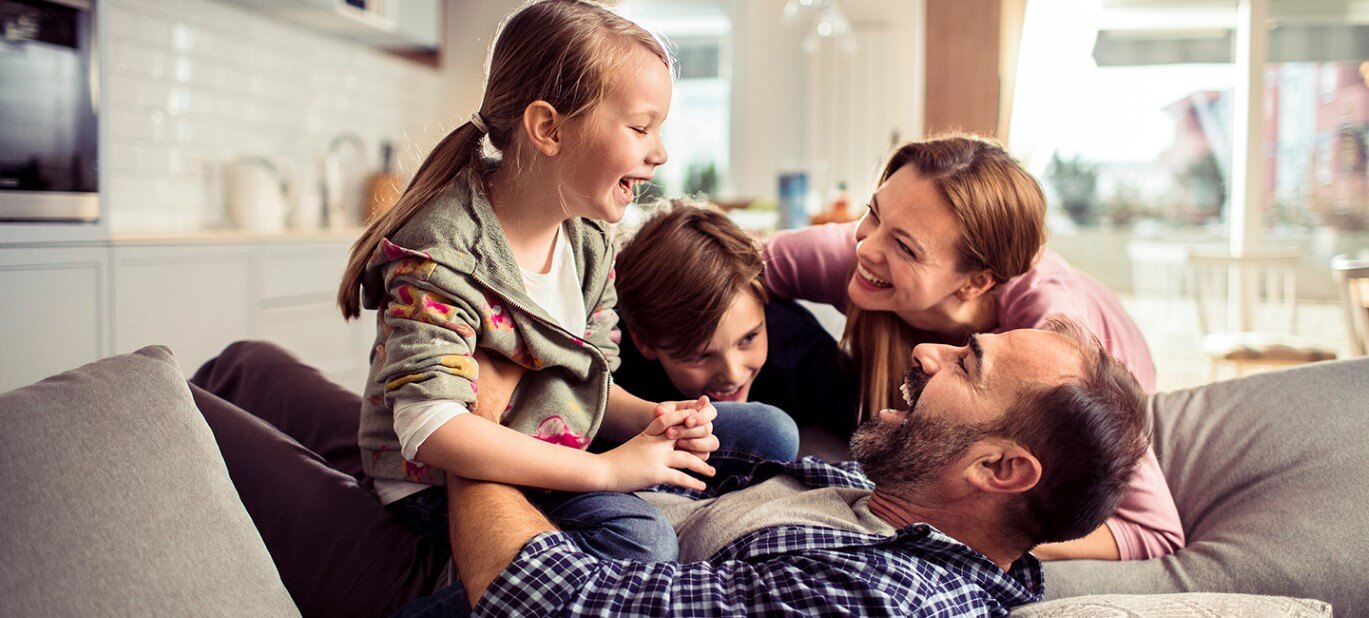 A dad, mom, daughter, and son playing together in a living room.