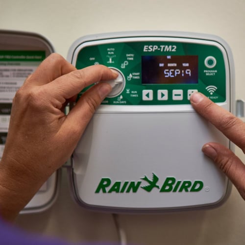 Hands adjusting an irrigation controller