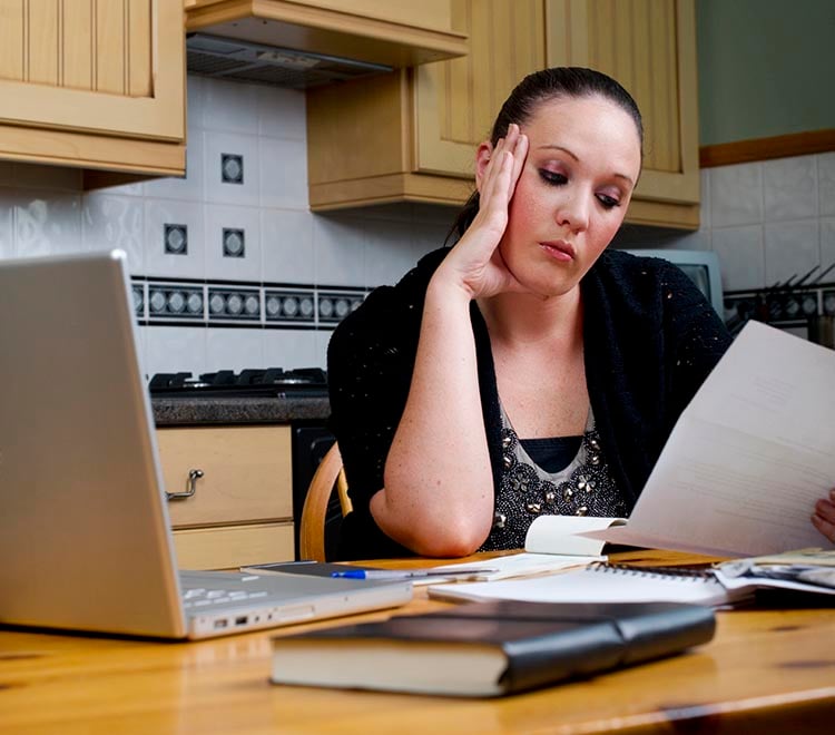 Person at table examines a paper bill.