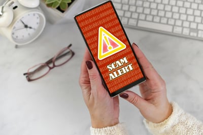 female-holding-a-phone-at-desk-with-scam-alert-war