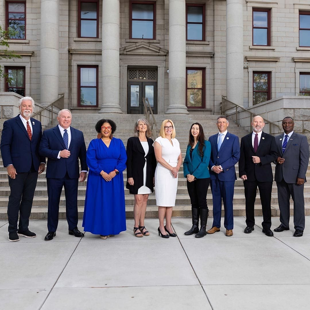 A group photograph of Colorado Springs Utilities Board members on the steps of city hall. Members pictured from left to right are David Leinweber, Ken Casey, Kimberly Gold, Nancy Henjum, Lynette Crow-Iverson, Brandy Williams, Brian Risley, Dave Donelson and Roland Rainey.
