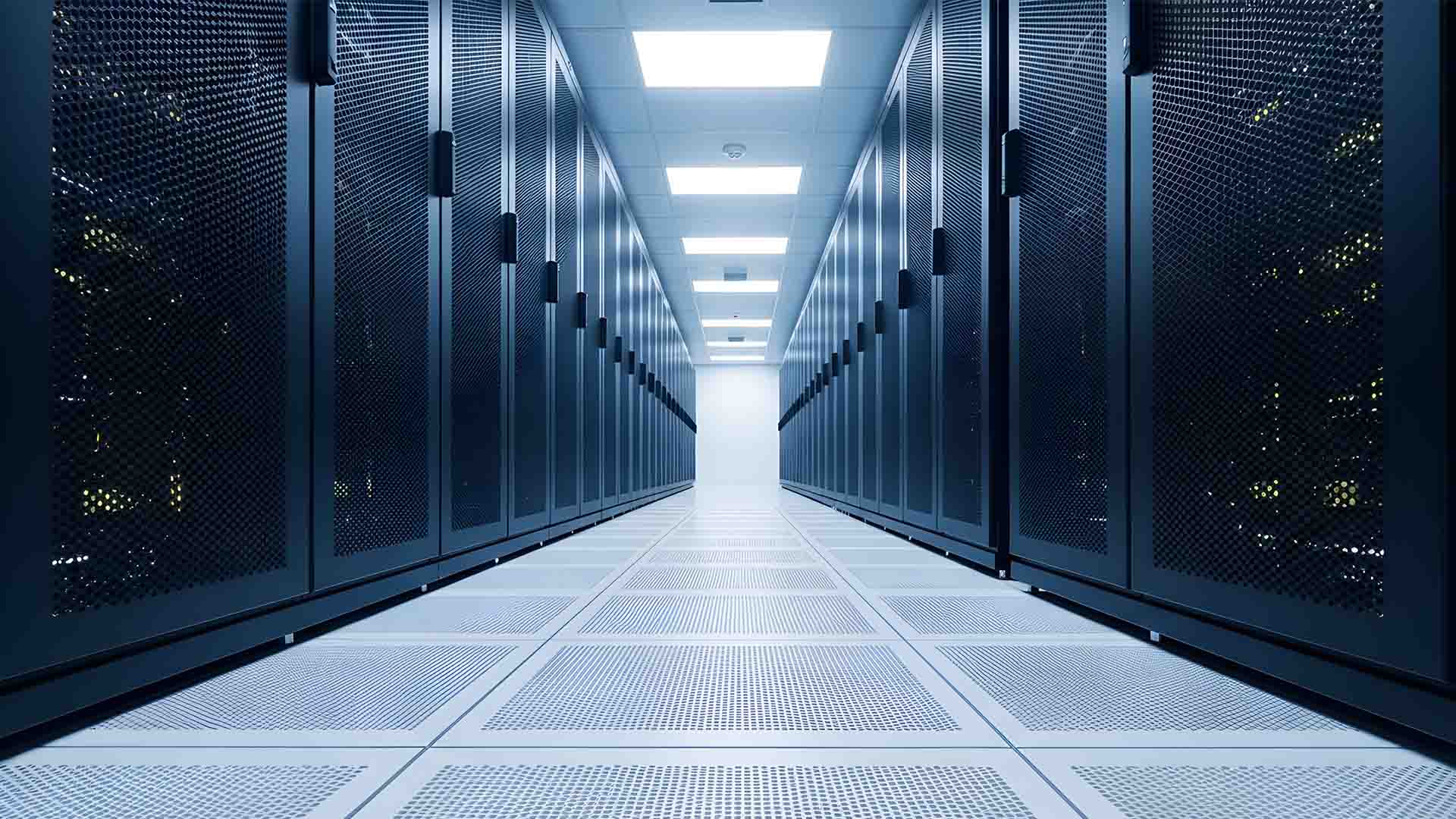 Interior shot of a data center, with black computer racks lined down a hallway under fluorescent lighting.