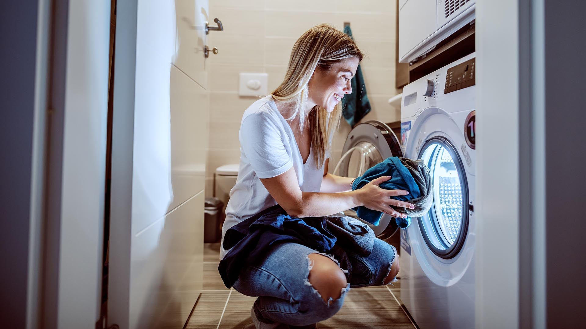 A person loading a washing machine with laundry.