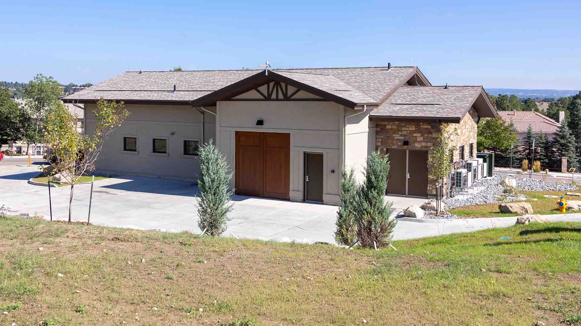 A stucco building resembling a suburban, single-family home with a driveway and landscaping surrounding it.