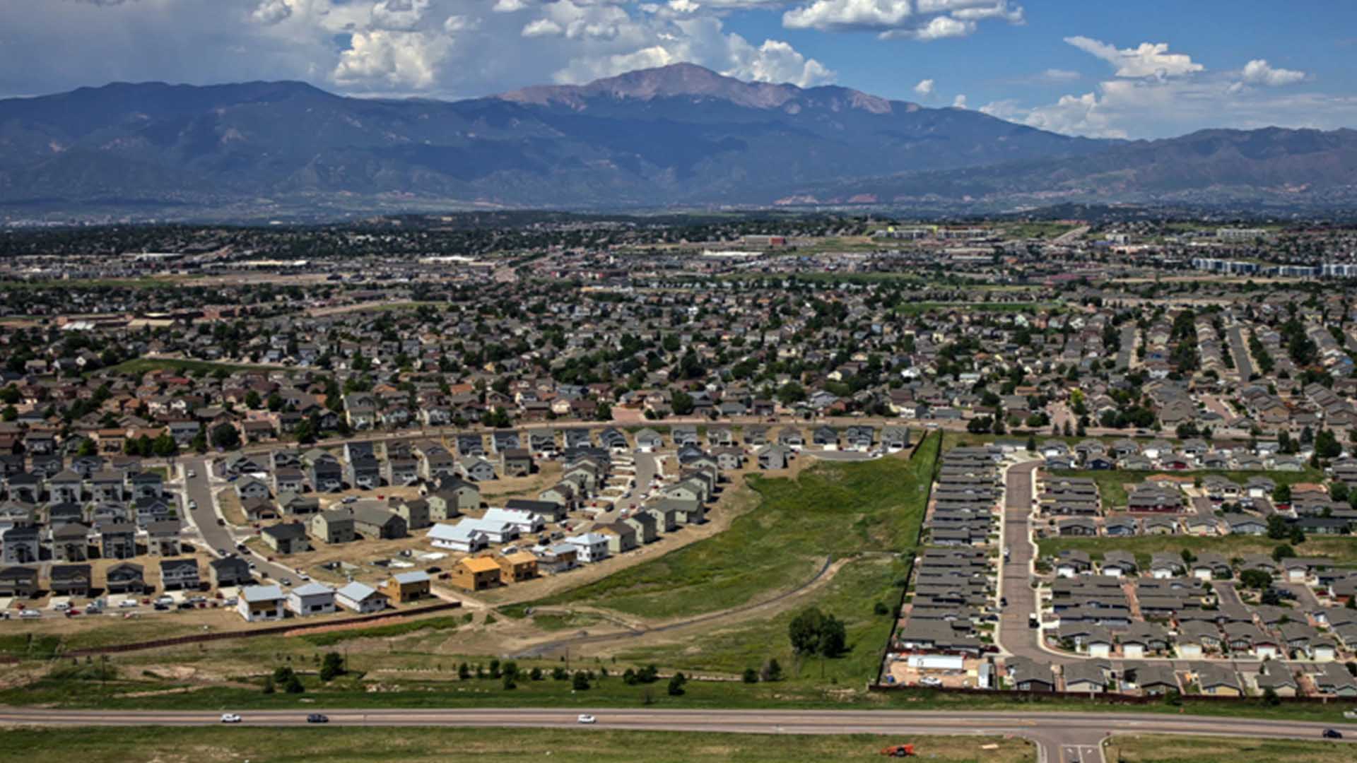 Aerial photo of the east side of Colorado Springs. Rows of houses stretch into the distance toward Pikes Peak. Several homes are under construction in the foreground.