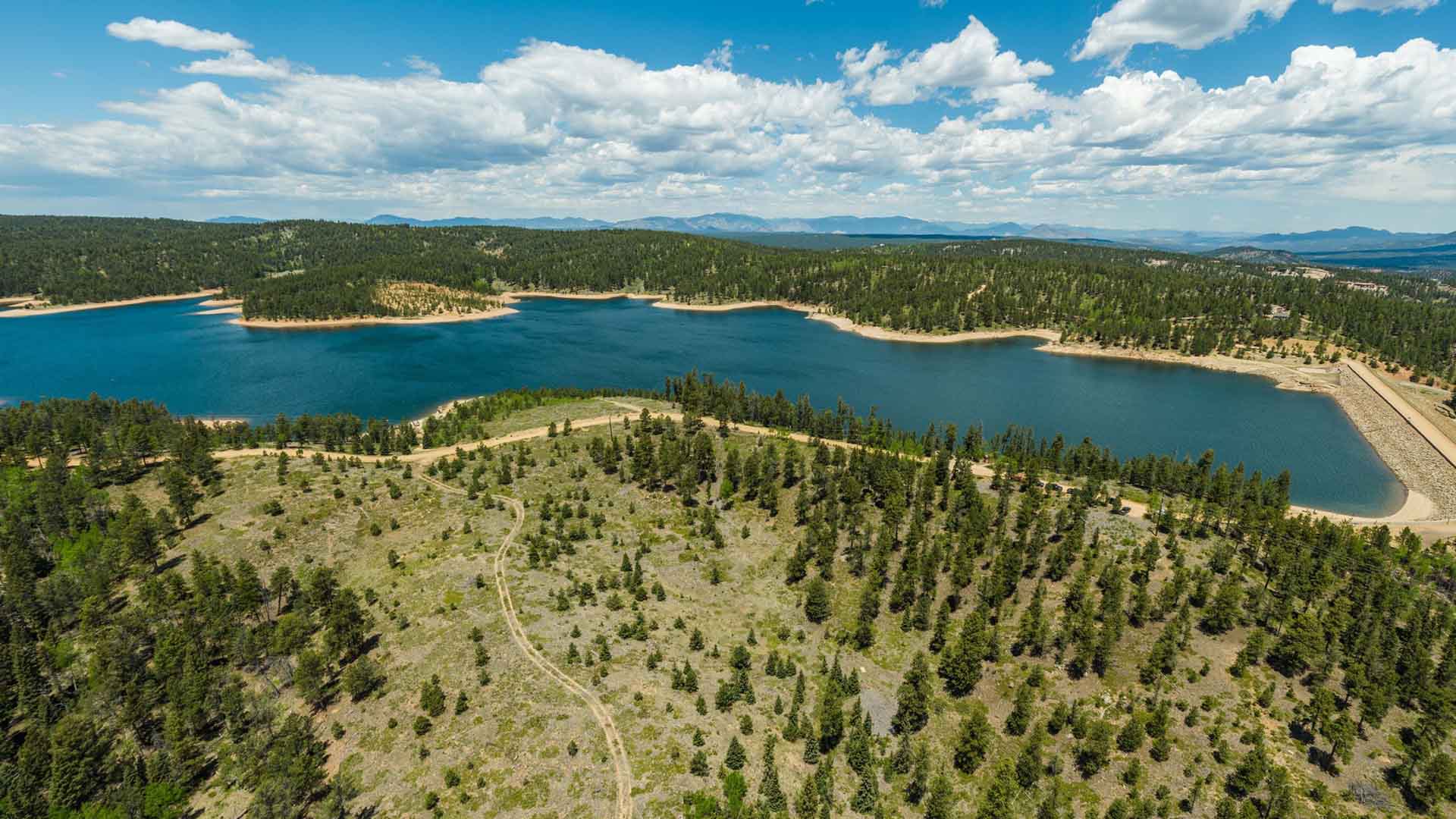 Aerial photo of the North Catamount Reservoir. The water is deep blue and surrounded by pine trees.