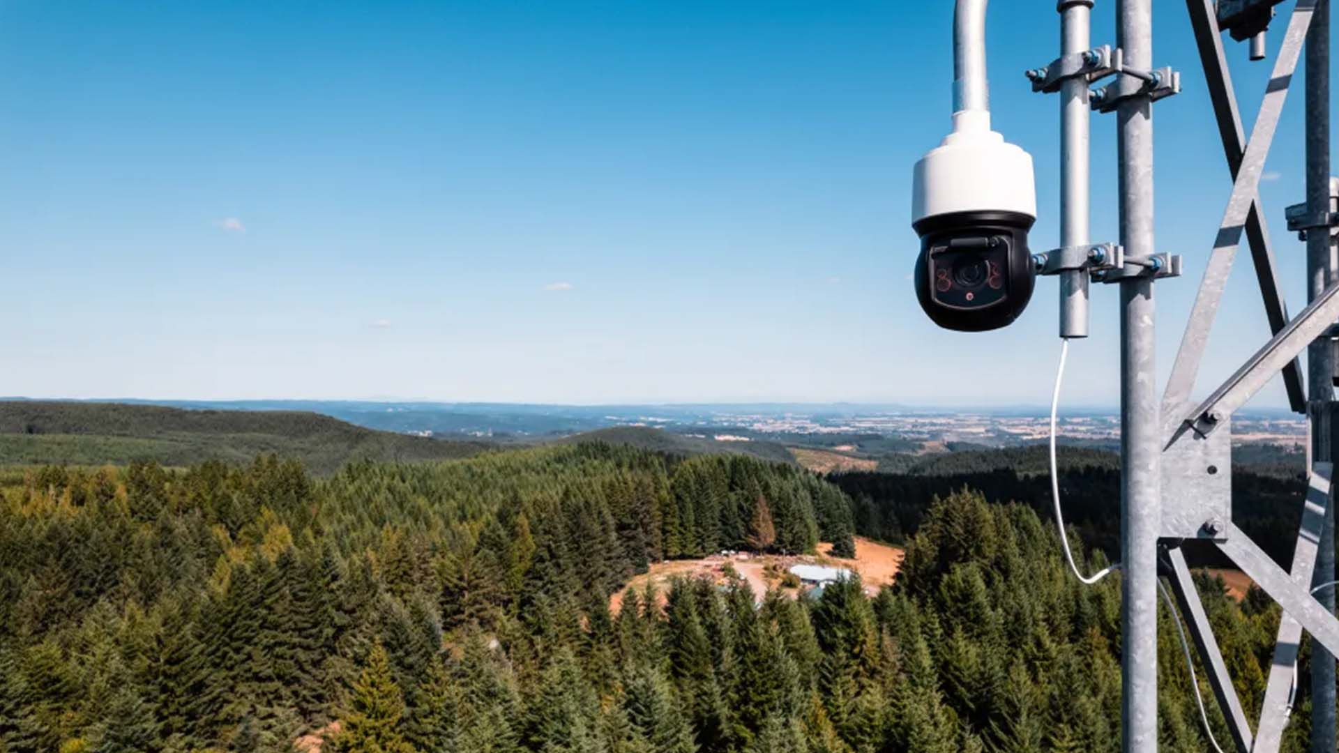 360-degree camera head mounted high off the ground on a steel tower in mountainous terrain.