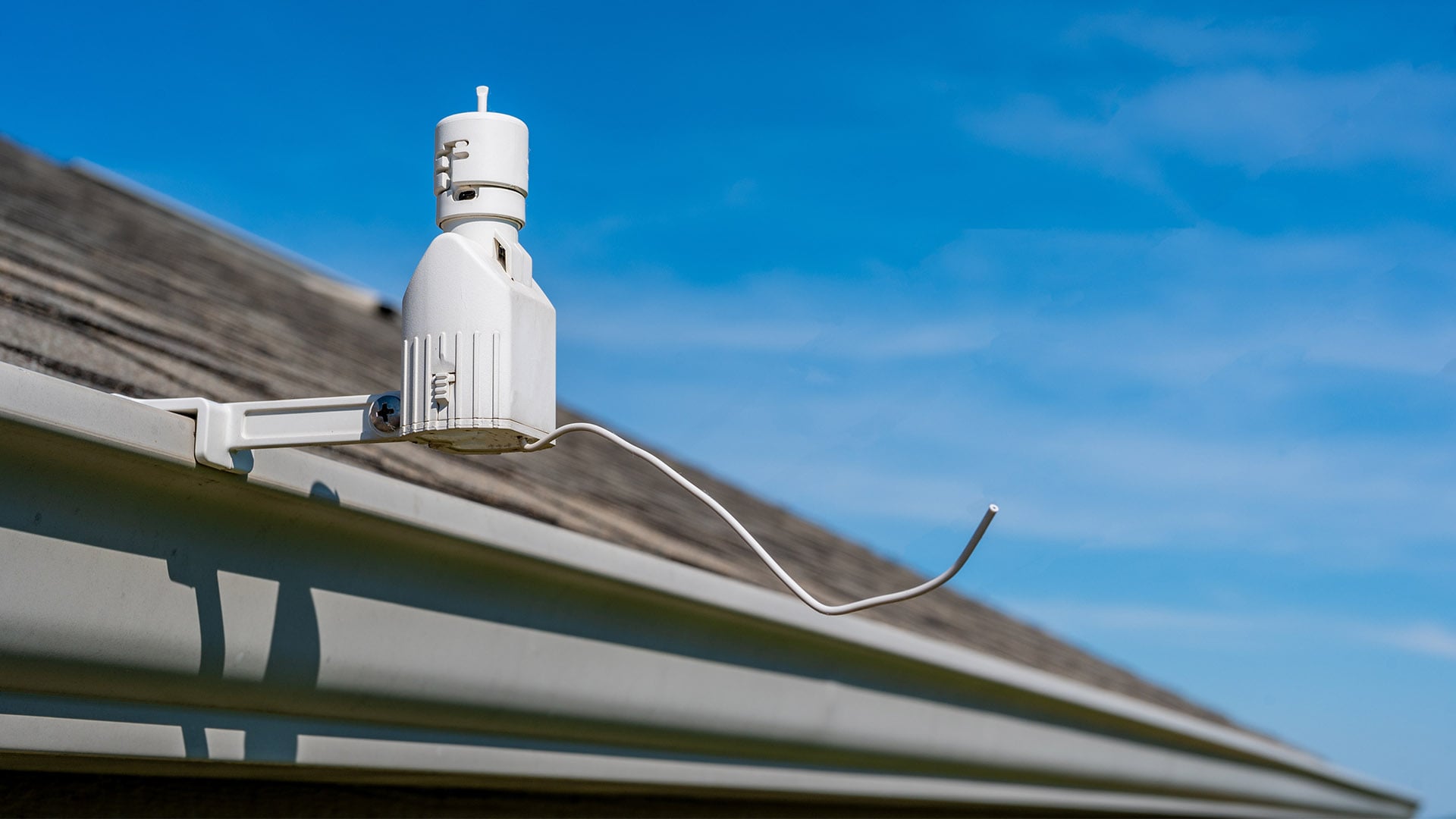 A cylindrical piece of outdoor equipment attached to a roof gutter.