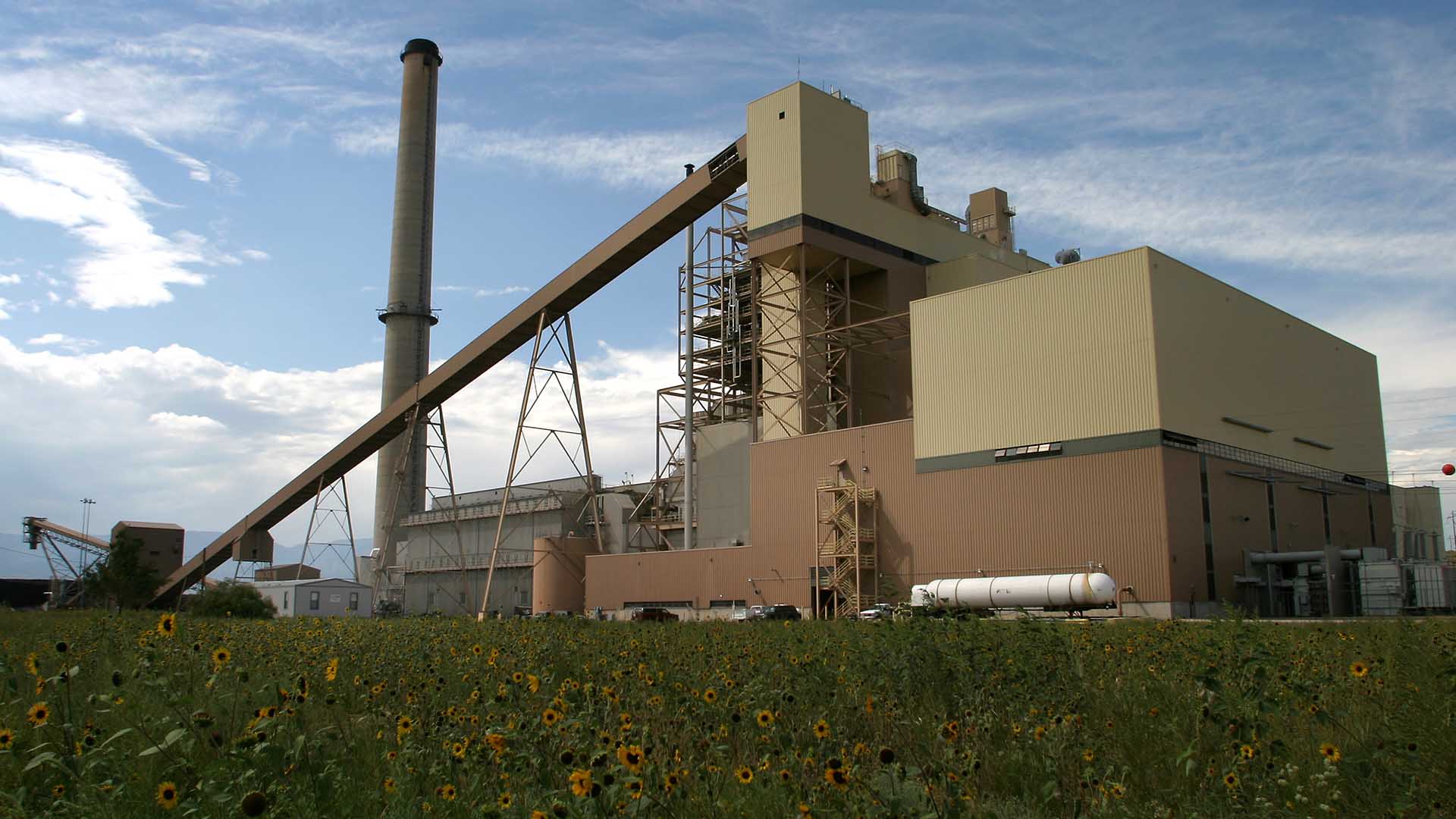 A tall smokestack and conveyor belt system next to a large industrial building.