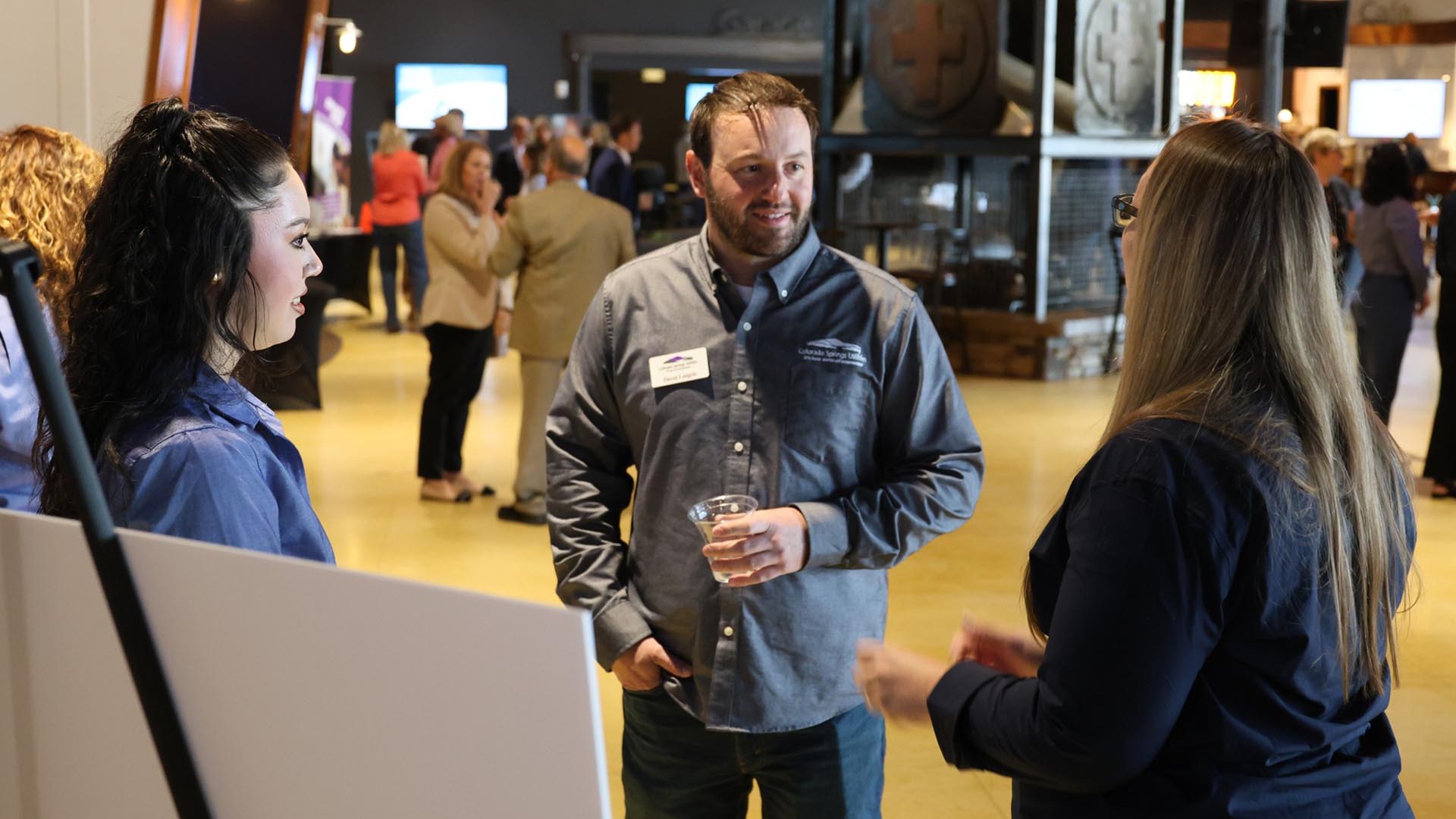 A Colorado Springs Utilities employee stands and talks to two customers at a community event.