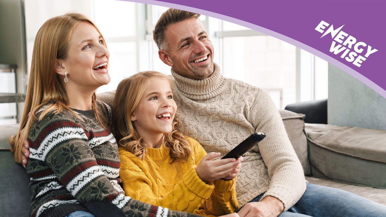 A family together on a couch looking at a TV.